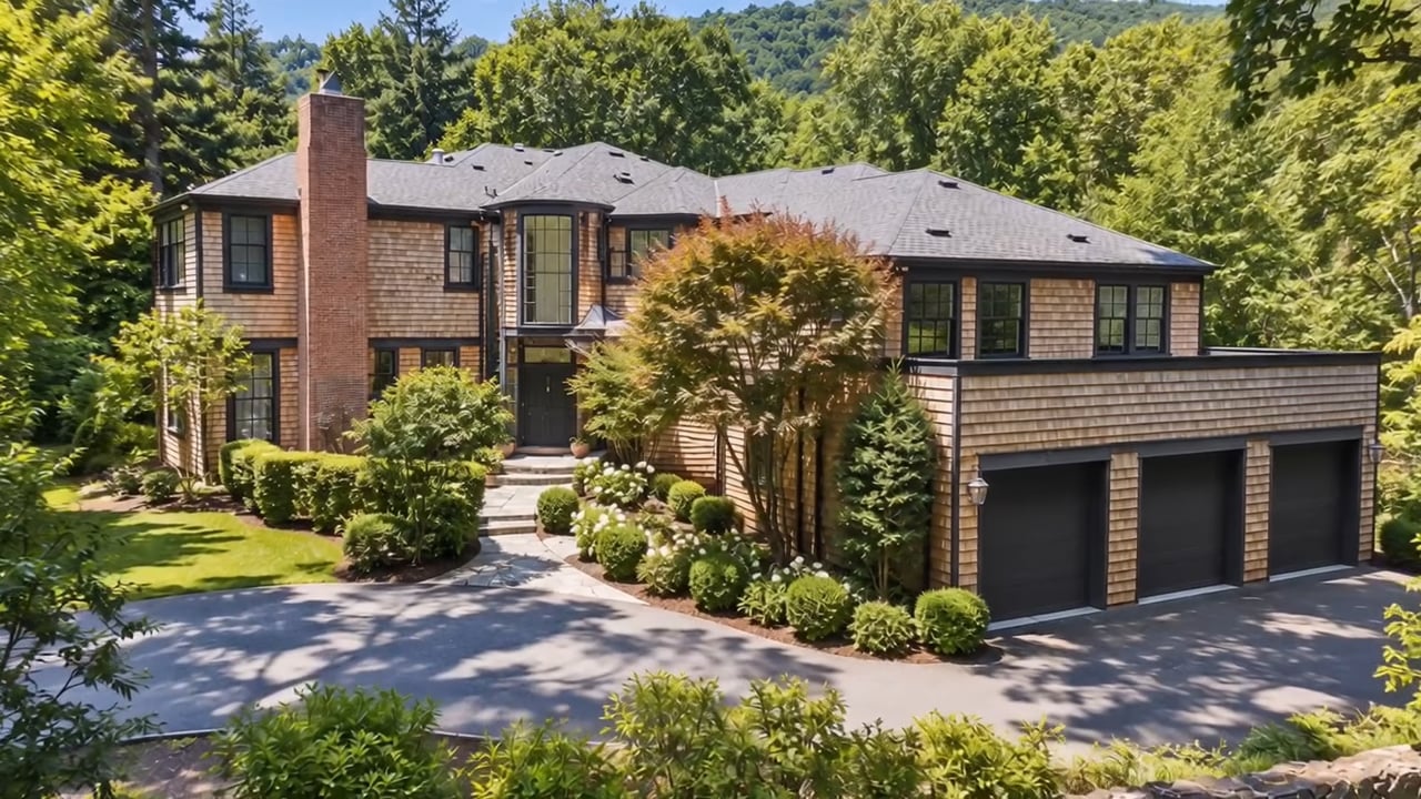 SKYLINE Listing: a shingled home with a three-car garage surrounded by mature trees.